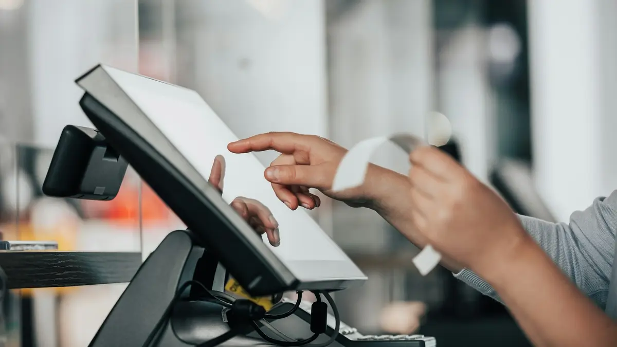 Client payant à la caisse d'un magasin, un ticket de caisse sortant de l'imprimante