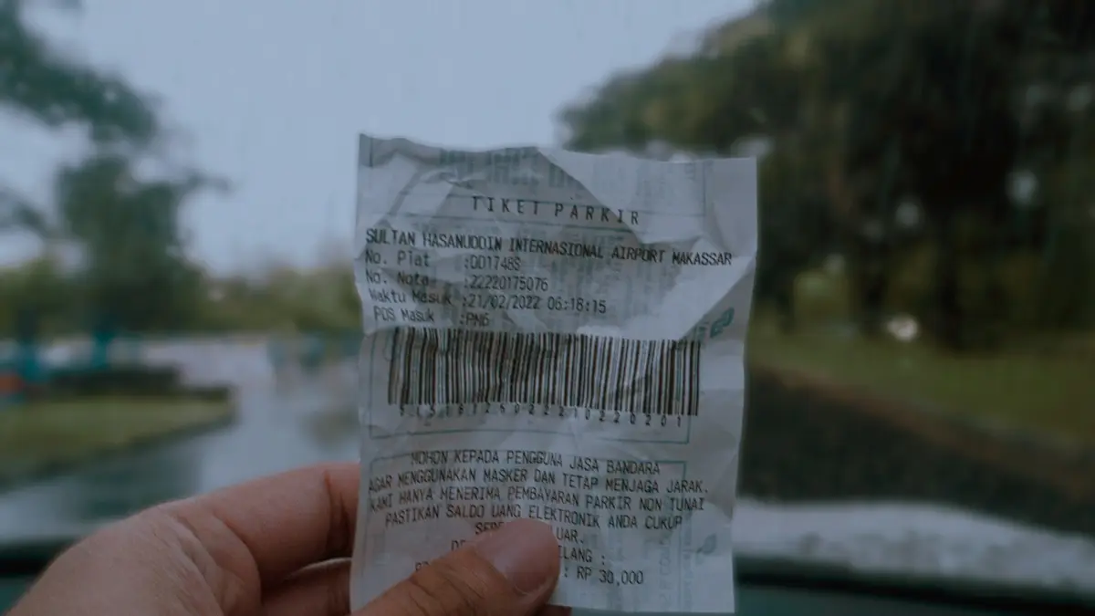 Hand holding a crumpled paper receipt, ready to be scanned with a phone